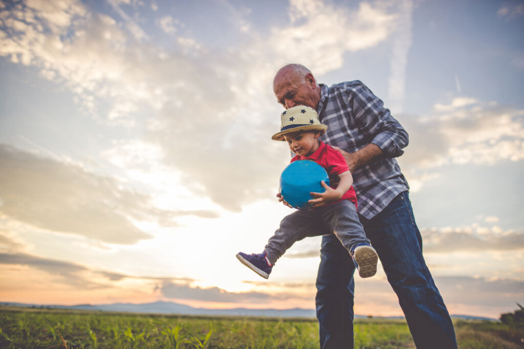Father playing with child who is holding a blue ball