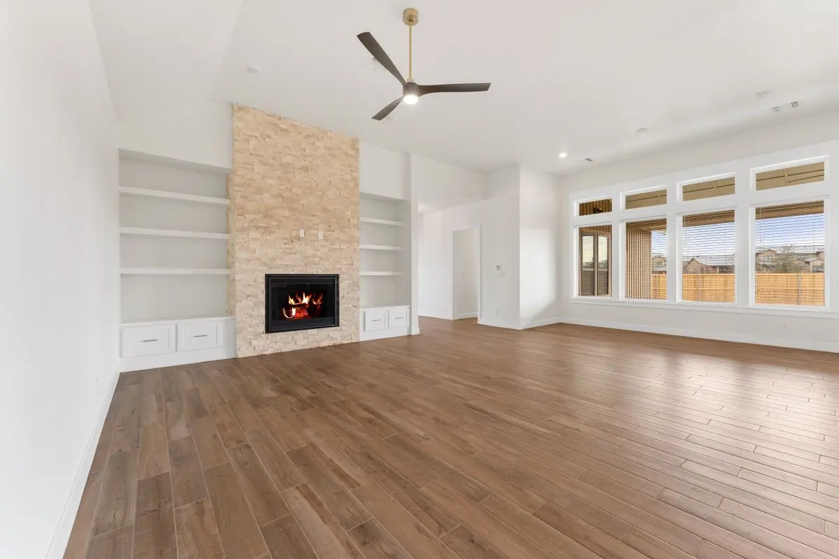 Empty living room view of a premium-designed home in The Vineyard Preserve. Spacious living room with a cozy fireplace. 